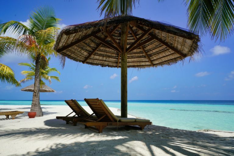 a couple lounge chairs under an umbrella on a beach