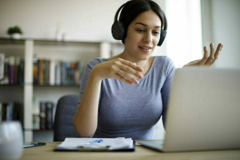 a woman wearing headphones and sitting in front of a laptop