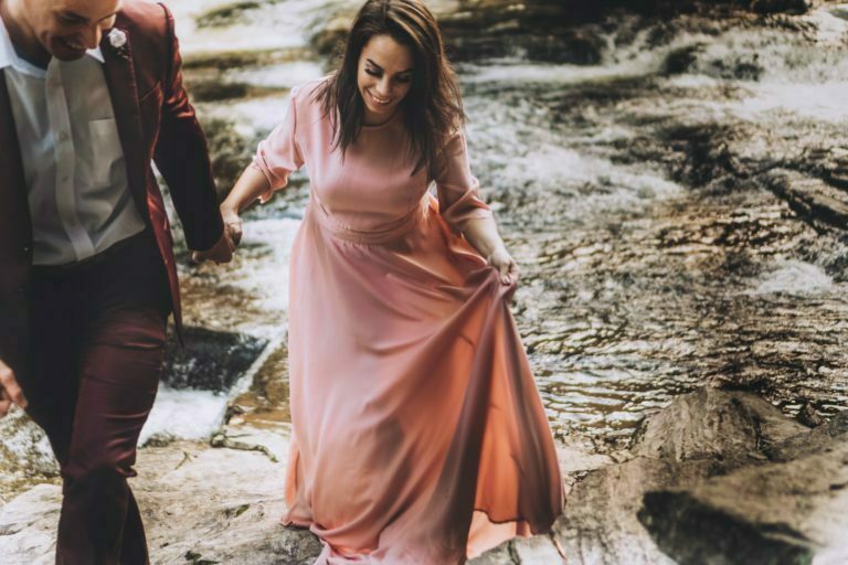a person in a pink dress walking on a rocky beach